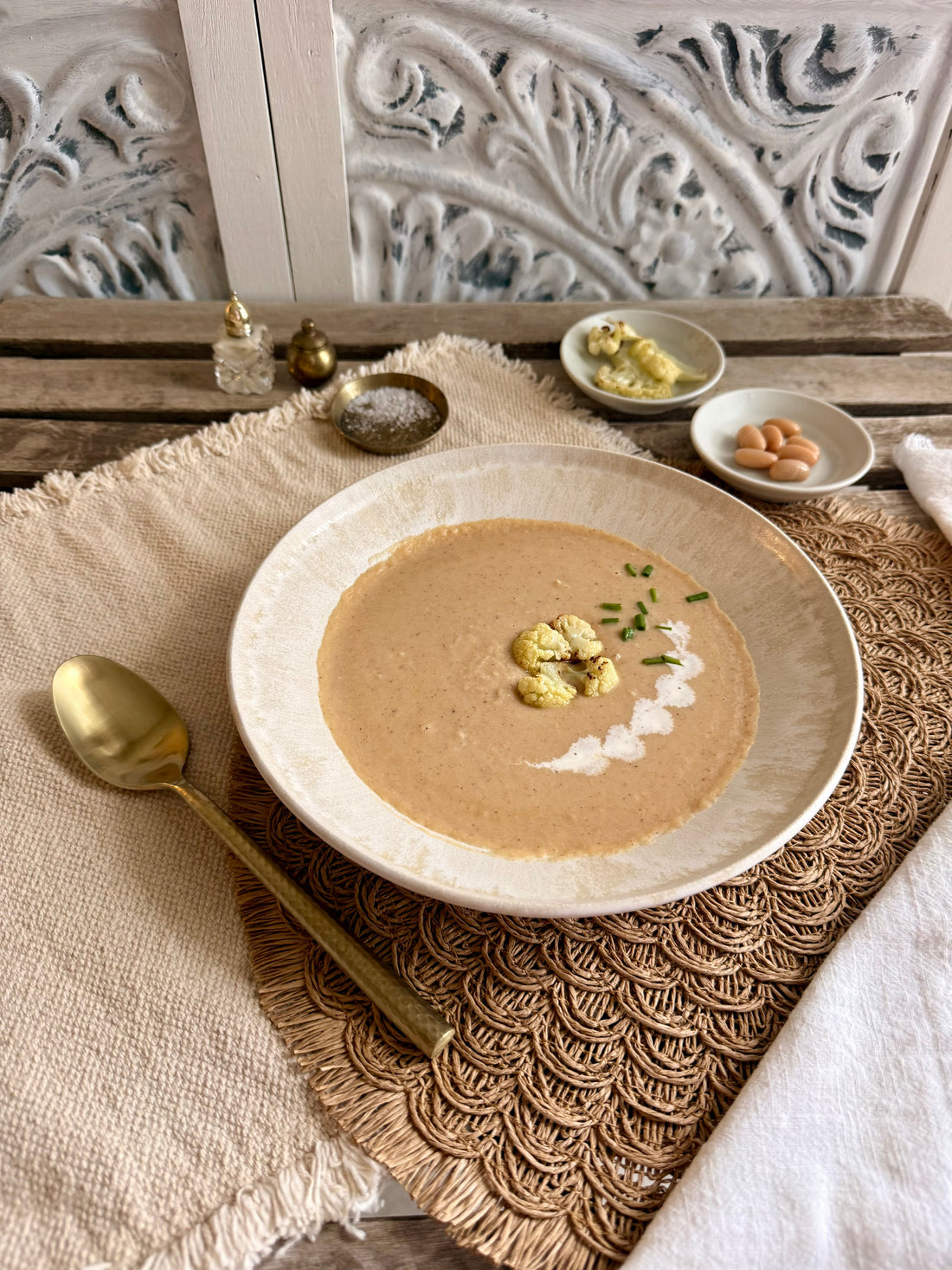 Roasted cauliflower and white bean velvet soup with roasted cauliflower florets and chives, served in a rustic bowl